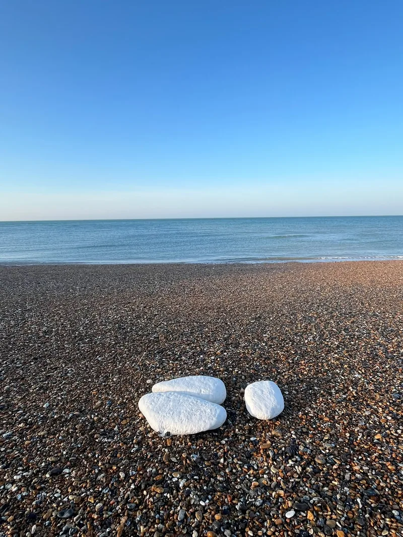 White stones resting on a shingle beach, the sea and open sky beyond